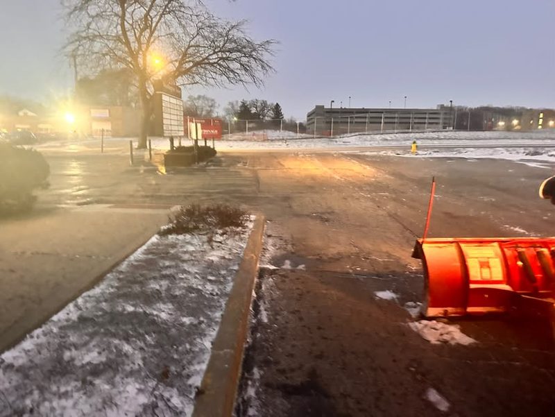 Plow blade at a commercial entrance with the curb line cleared.