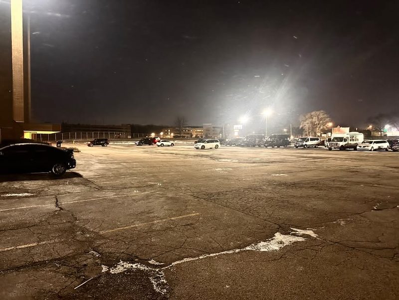 A large lot cleared at night with snow still falling.