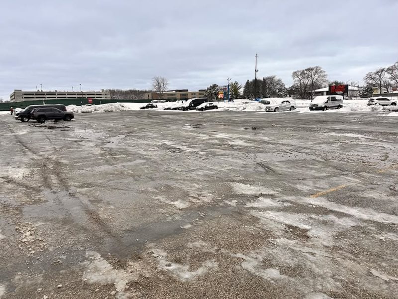 A wide commercial lot cleared to pavement with snow banked at the edges.