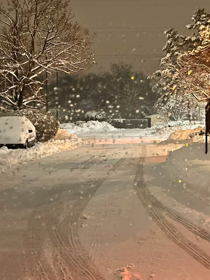 A residential street and driveway during heavy overnight snowfall.